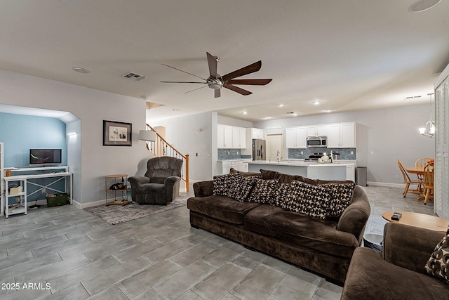 living room with ceiling fan with notable chandelier and sink