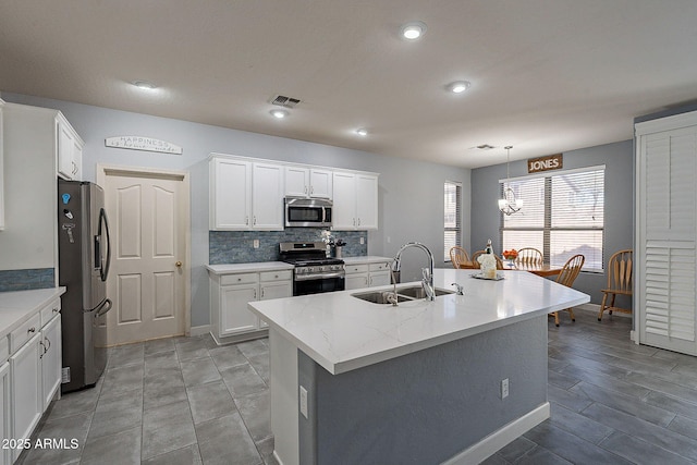 kitchen featuring stainless steel appliances, white cabinets, sink, and a kitchen island with sink