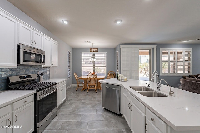 kitchen featuring stainless steel appliances, sink, white cabinets, decorative backsplash, and hanging light fixtures