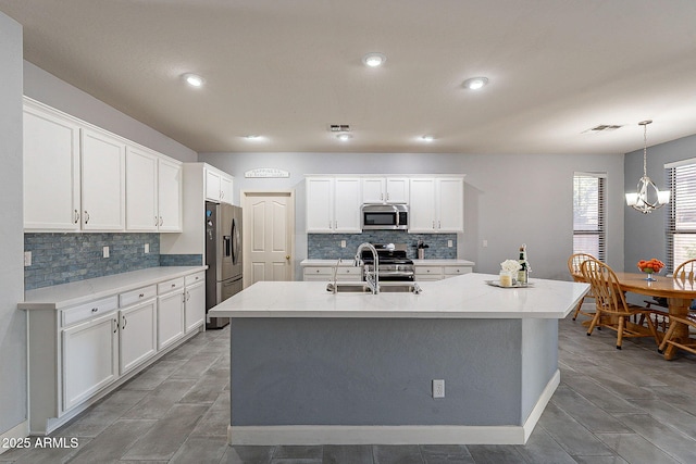 kitchen with white cabinets, appliances with stainless steel finishes, and a kitchen island with sink