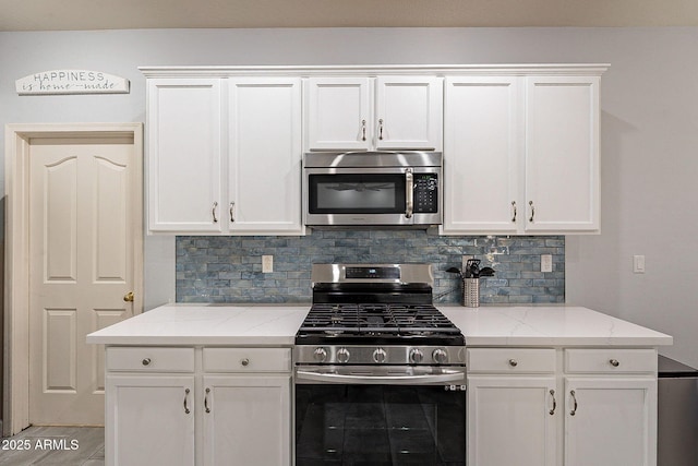 kitchen with stainless steel appliances, decorative backsplash, and white cabinetry