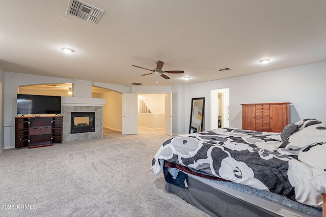 carpeted bedroom featuring a fireplace and ceiling fan