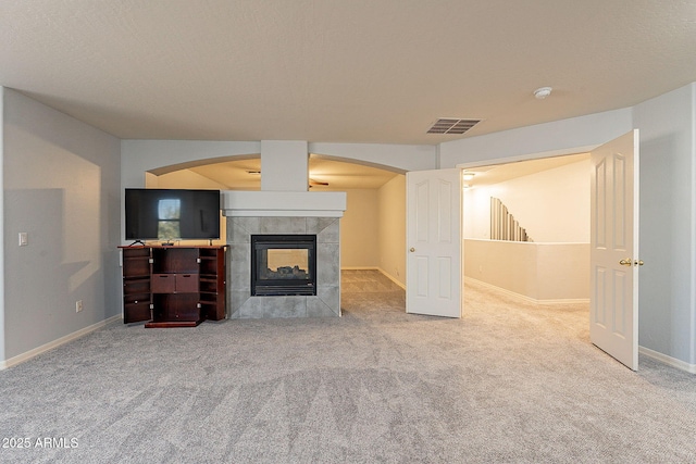 unfurnished living room featuring a tile fireplace and carpet