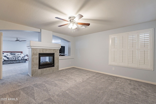 unfurnished living room with a fireplace, carpet floors, and ceiling fan