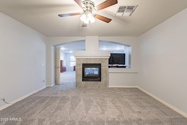 unfurnished living room with a fireplace, ceiling fan, and light colored carpet