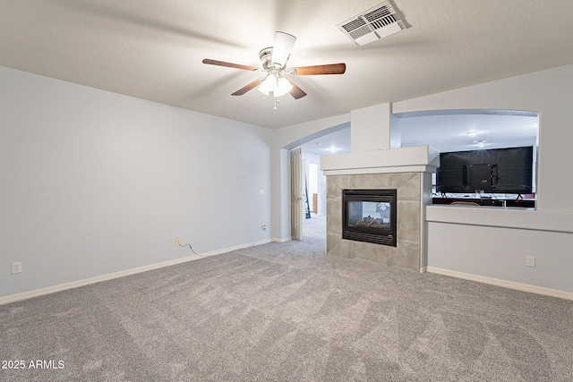 unfurnished living room with a tile fireplace, light carpet, and ceiling fan