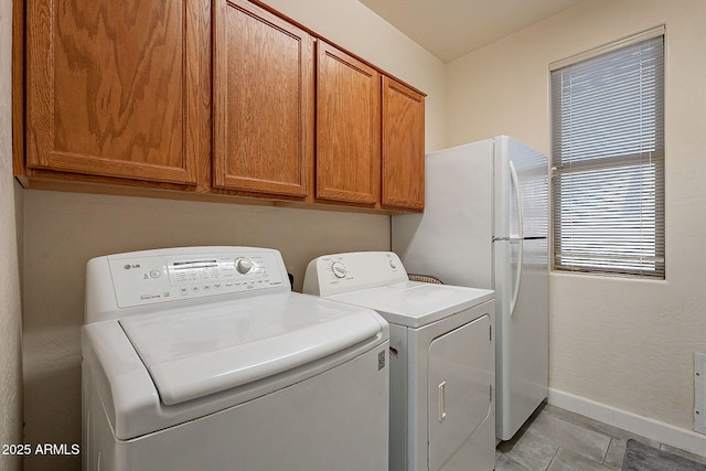 clothes washing area featuring separate washer and dryer, cabinets, and light tile patterned floors