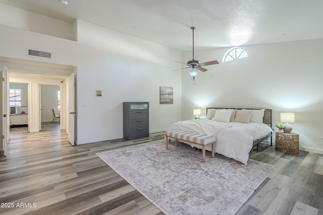 bedroom featuring ceiling fan, wood-type flooring, and multiple windows