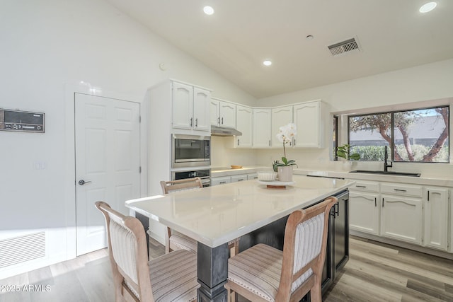 kitchen featuring white cabinets, a kitchen breakfast bar, sink, and stainless steel appliances