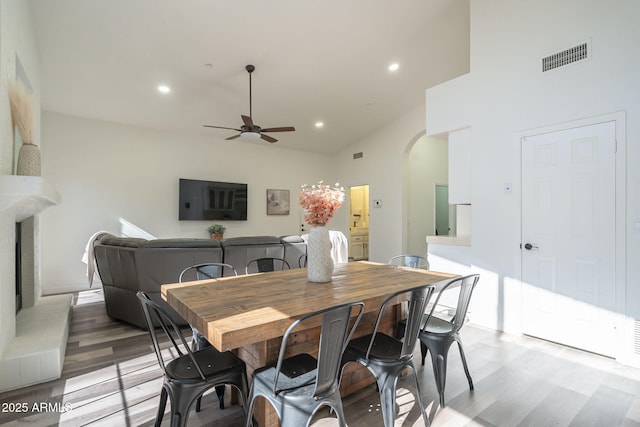 dining area with hardwood / wood-style flooring, ceiling fan, and high vaulted ceiling