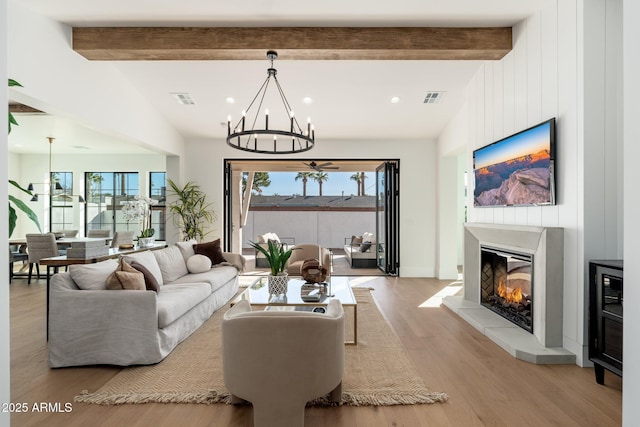 living room with lofted ceiling with beams, light wood-type flooring, a wealth of natural light, and a chandelier