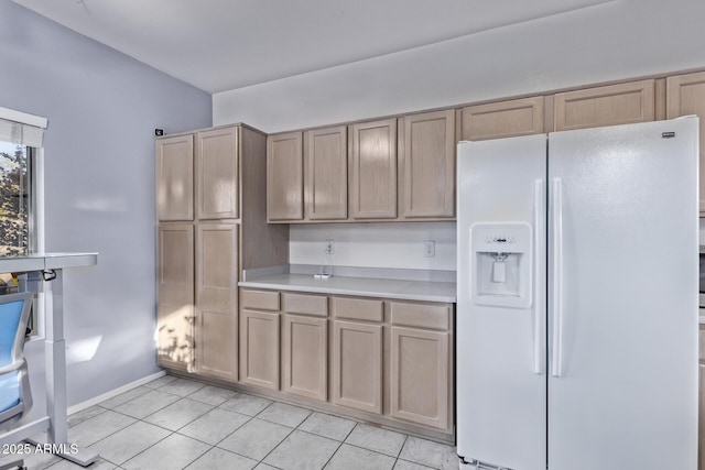 kitchen with white fridge with ice dispenser, light tile patterned floors, and light brown cabinetry