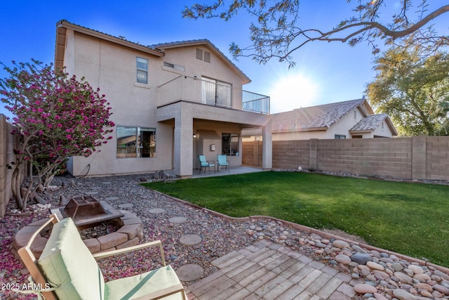 back of house with a fire pit, a balcony, a lawn, and a patio area