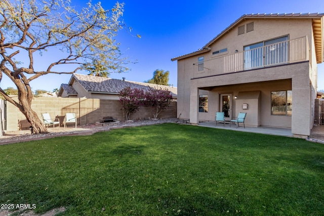 back of house featuring a balcony, a patio area, and a lawn