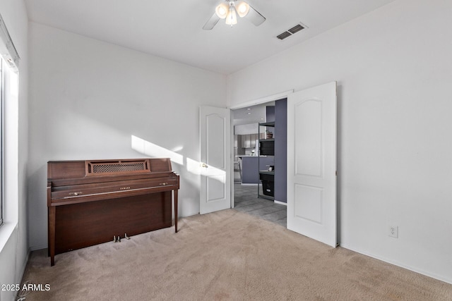 interior space featuring ceiling fan and light carpet