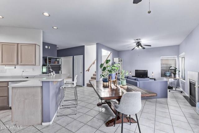 kitchen with a breakfast bar area, light brown cabinets, ceiling fan, and kitchen peninsula