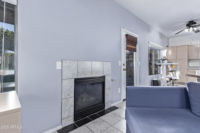 tiled living room with a tiled fireplace and ceiling fan