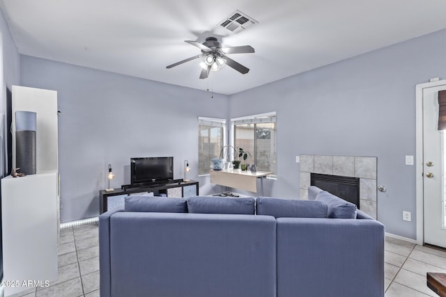 living room featuring light tile patterned floors, a fireplace, and ceiling fan