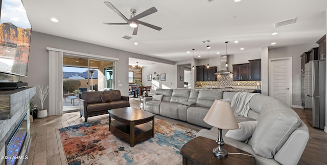 living room with ceiling fan, a fireplace, and light hardwood / wood-style flooring