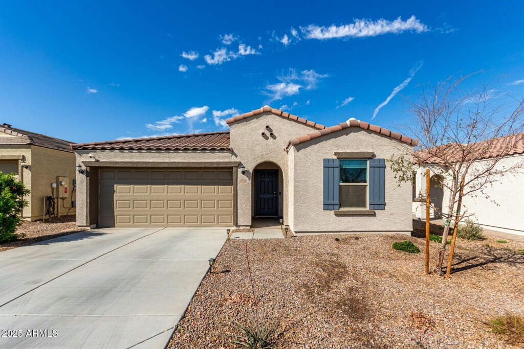 mediterranean / spanish-style home with a garage, concrete driveway, a tiled roof, and stucco siding