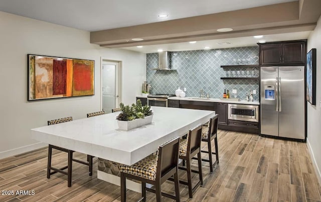 2511 W Queen Creek Rd Unit 374, Chandler, AZ 85248 - kitchen with stainless steel appliances, wall chimney exhaust hood, a sink, light wood-style floors, and tasteful backsplash