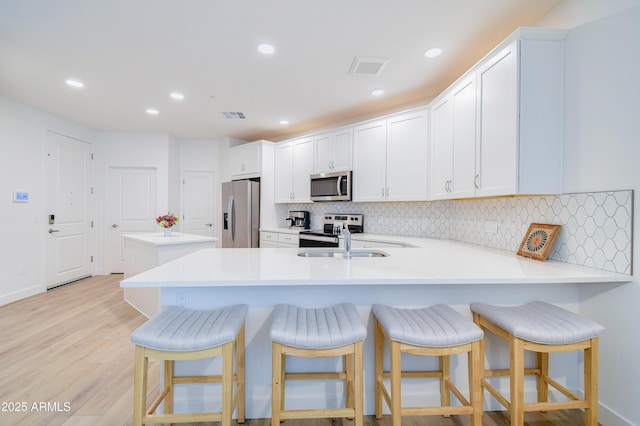 2511 W Queen Creek Rd Unit 374, Chandler, AZ 85248 - kitchen with appliances with stainless steel finishes, tasteful backsplash, a peninsula, light countertops, and recessed lighting