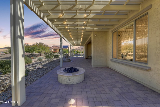 patio terrace at dusk featuring an outdoor fire pit and a pergola