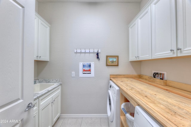 clothes washing area with cabinets, washer / dryer, sink, and light tile patterned floors