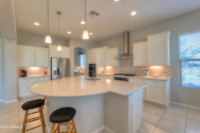 kitchen with light tile patterned flooring, white cabinetry, tasteful backsplash, appliances with stainless steel finishes, and wall chimney range hood