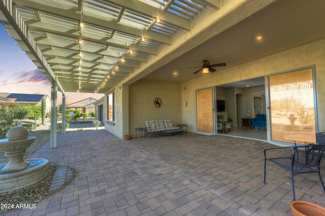 patio terrace at dusk featuring ceiling fan and a pergola