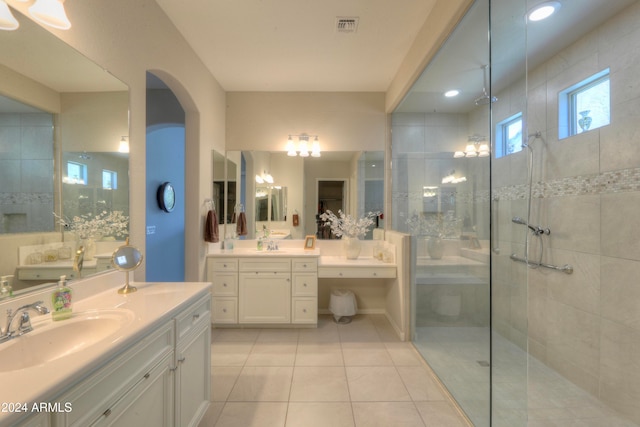 bathroom with tile patterned flooring, vanity, and tiled shower