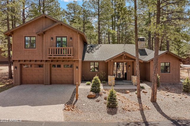 rustic home featuring roof with shingles, a chimney, french doors, and decorative driveway