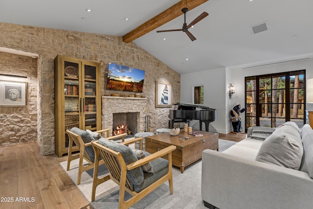 living room featuring a ceiling fan, light wood-style flooring, lofted ceiling with beams, and a fireplace