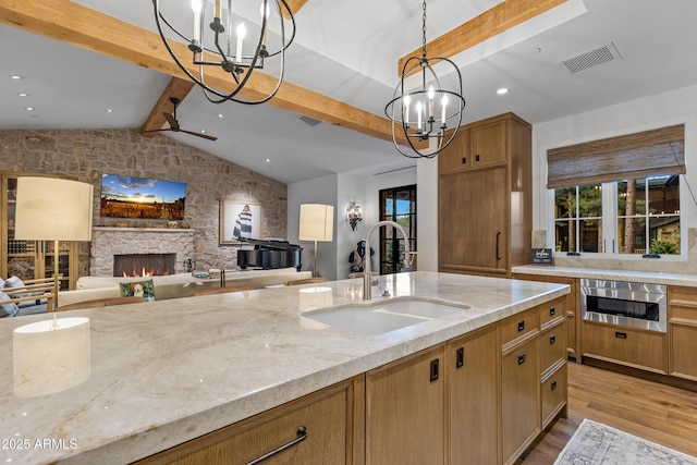 kitchen featuring a chandelier, light stone counters, visible vents, and a sink