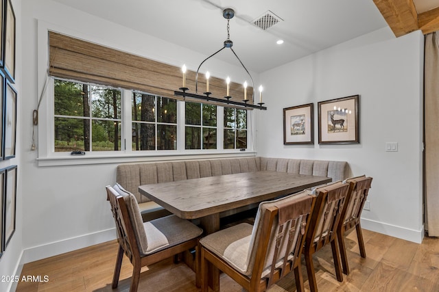 dining area with breakfast area, baseboards, visible vents, and wood finished floors