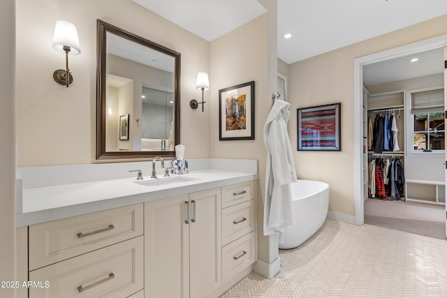 full bathroom featuring vanity, baseboards, a freestanding bath, and recessed lighting