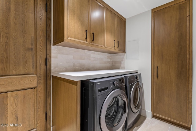 clothes washing area featuring washing machine and dryer, cabinet space, and light tile patterned floors