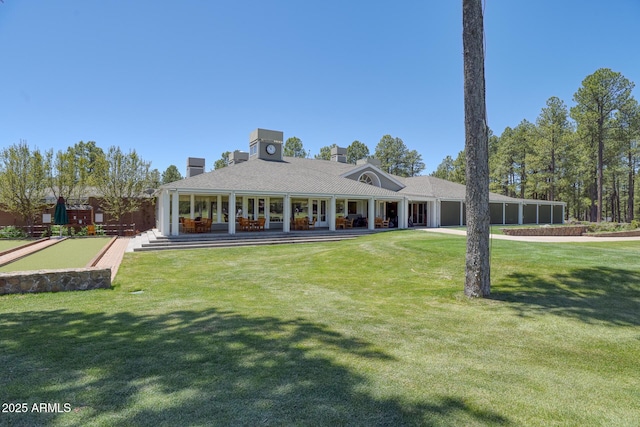 rear view of house featuring a garage, a chimney, and a lawn