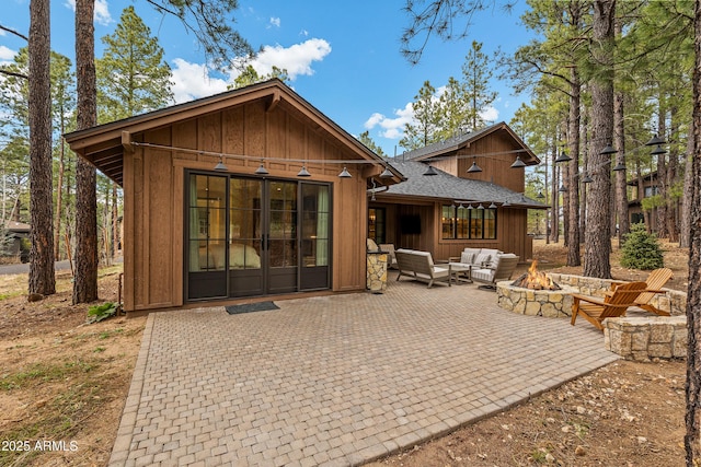 back of property featuring an outdoor living space with a fire pit, a patio, a shingled roof, and board and batten siding