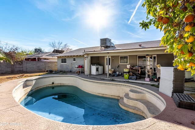 view of pool featuring a hot tub, a patio area, washer / dryer, cooling unit, and a fenced backyard