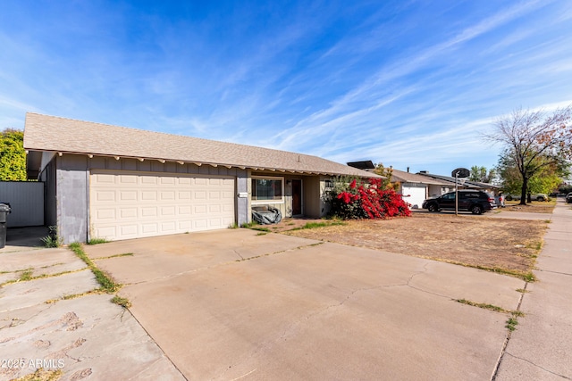 single story home featuring concrete driveway, a shingled roof, and an attached garage