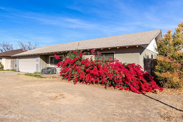 single story home with a garage and roof with shingles