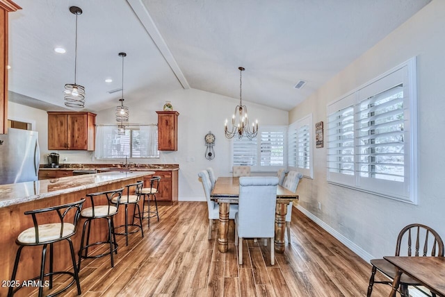 dining room featuring light wood-style flooring, baseboards, visible vents, and vaulted ceiling with beams