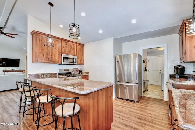 kitchen featuring brown cabinetry, light wood finished floors, stainless steel appliances, and a sink
