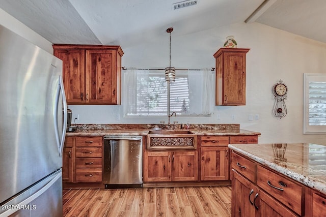kitchen featuring brown cabinets, lofted ceiling with beams, light wood-type flooring, visible vents, and appliances with stainless steel finishes