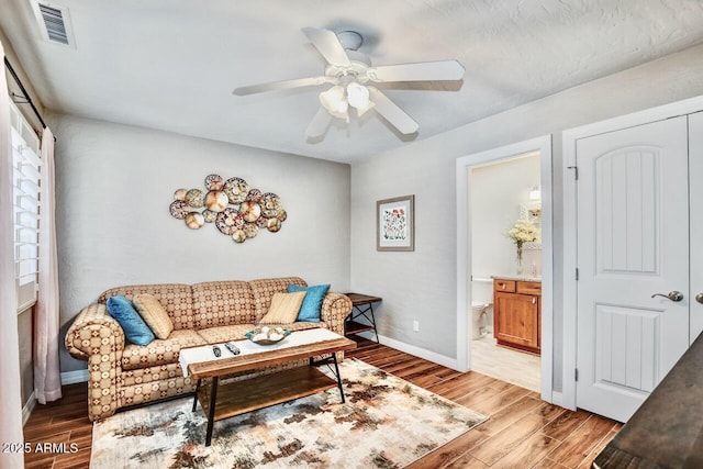 living area featuring ceiling fan, baseboards, visible vents, and light wood-style floors