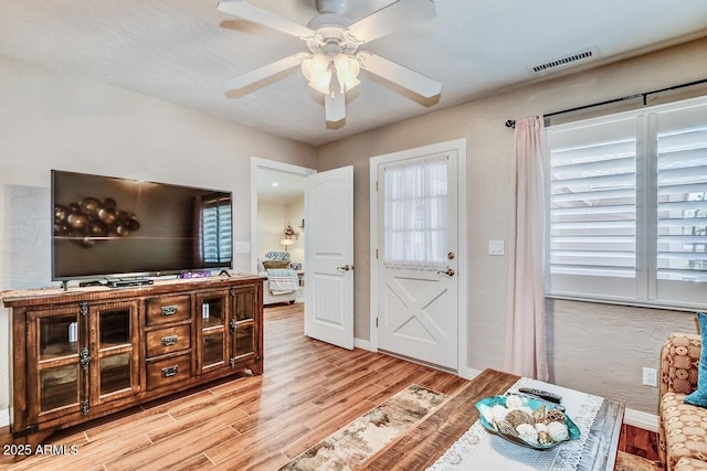 living area with a ceiling fan, baseboards, light wood finished floors, and visible vents