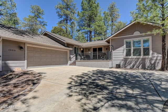ranch-style home with concrete driveway, roof with shingles, and an attached garage