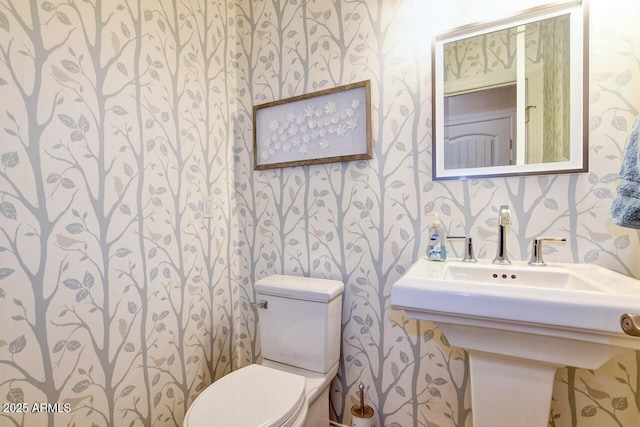 half bathroom featuring toilet and wallpapered walls