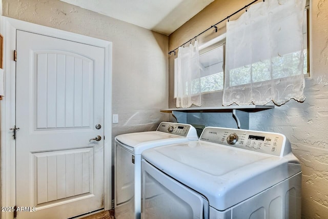 clothes washing area featuring laundry area, independent washer and dryer, and a textured wall